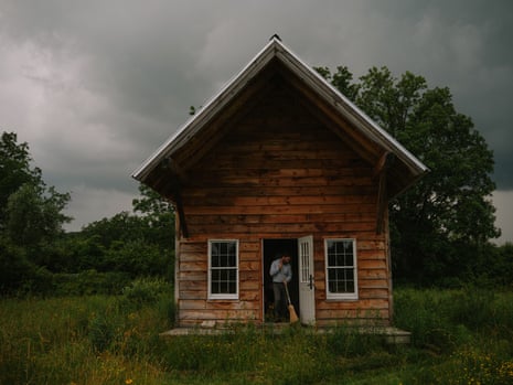 Man sweeping in the doorway of a wooden cabin
