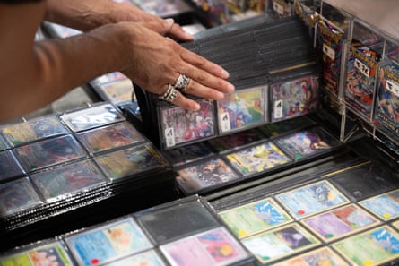 A visitor browses through a Pokémon card binder at a Trading Card Game vendor booth.