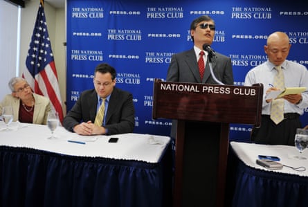 man speaks at podium with several seated next to him