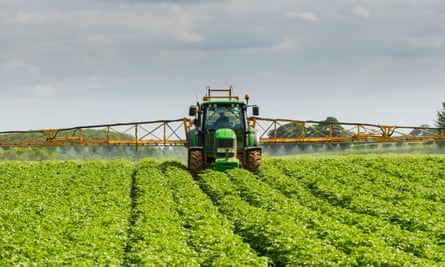 Um trator pulverizando campos com pesticidas