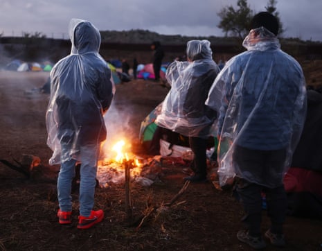 people stand near fire, viewed from behind