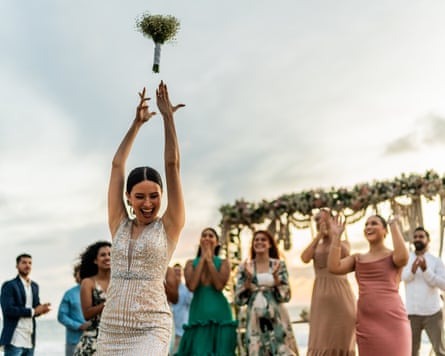 Bride throwing the bouquet to her friends on the beach wedding party