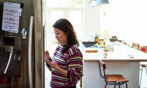Mid adult woman checking food in fridge holding tablet