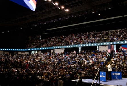 Politics tamfitronics woman wearing white suit stands behind podium and speaks to large crowd in arena
