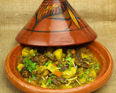 Beef stew in a shallow earthenware cooking dish with a tall, conical lid