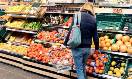 A woman shopping for fruit in Tesco supermarket aisle.