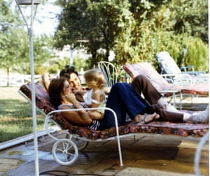 Priscilla and Elvis Presley play with a young Lisa Marie on lounge chairs outside