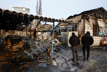 Two people look at a badly damaged building