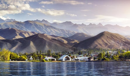 A group of white buildings between a lake and mountains