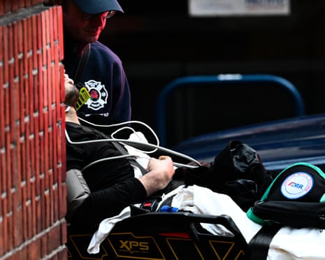 an emergency worker pushes a man on a gurney outside