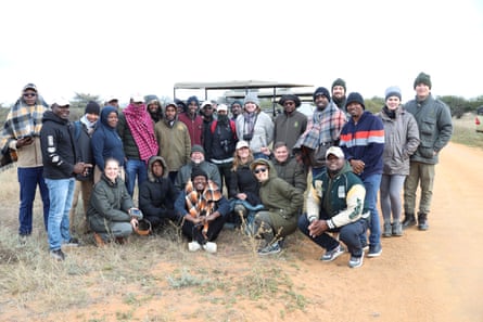 A group of people pose for a group shot in a wildlife reserve.