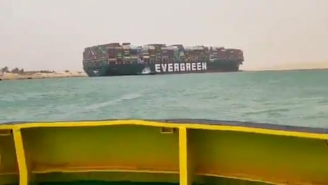 Container ship runs aground in Suez canal causing traffic jam – video