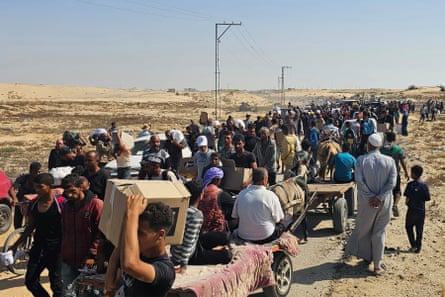 Displaced Palestinians walk along a road carrying belongings