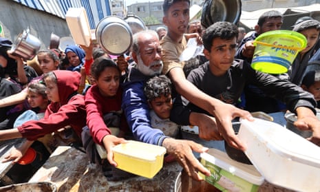 Palestinians queue at a charity kitchen at the Nuseirat refugee camp in the central Gaza Strip on Sunday