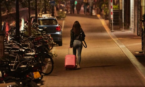 Woman walking the streets of Amsterdam with a suitcase.