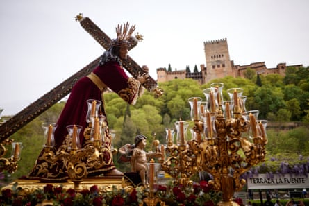 A float with a statue of the Jesus passes in front of the Alhambra, Granada