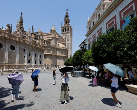Tourists protect themselves from the hot sun with umbrellas during the first summer heatwave in Seville, southern Spain.