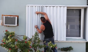 Anthony Perrone pulls the hurricane shutters closed on his home as Hurricane Isaias approaches Florida
