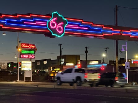 Traffic passes under a neon Route 66 sign over the road