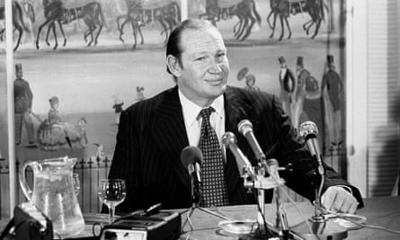 Kerry Packer sits at a desk in front of microphones