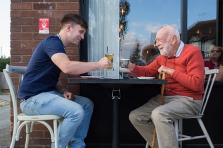 Two men sitting opposite each other at a table outside a restaurant