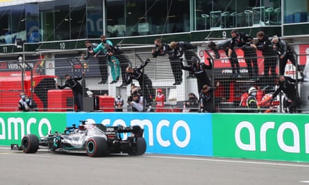 Mercedes’ Lewis Hamilton crosses the finish line as his team celebrate at the side of the track