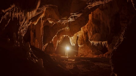 A man with a head torch walks through the Chauvet cave.