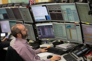 A trader studies information on trading screens at ETX Capital.