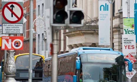 Buses pass signposts covered in placards from the ‘Yes’ and ‘No’ campaigns in Dublin on Thursday