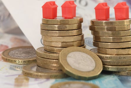 Model houses on a pile of coins and bank notes.