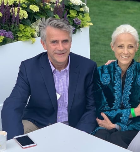 Christopher and Katharine Harborne dressed smartly, sitting next to each other at a white table, with flowers in the background