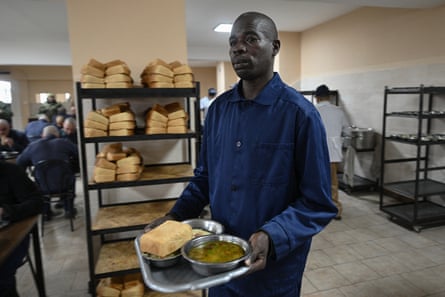 Evans in a dark blue prison uniform carrying his lunch tray across a cafeteria