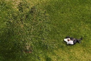 An office worker enjoys their lunchtime near a tree by City Hall on Southbank, London