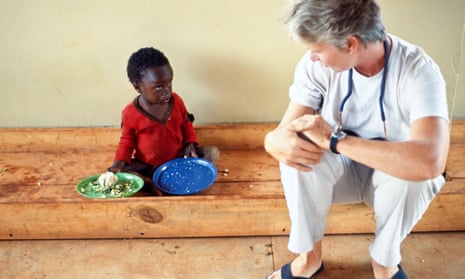 Female health worker talking to a small boy who has Aids in an orphanage in Mbala, Zambia