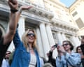 In sunglasses, a white vest and blue denim shirt, Silvia Salis, the mayor of Genoa, waves to a surrounding crowd