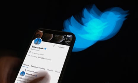 Elon Musk's Twitter page displayed on the screen of a smartphone with Twitter logo in the background