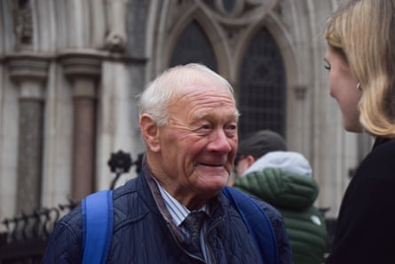 Barry Laycock stands outside the Royal Courts of Justice talking to a young woman. He has short white hair and wears a blue jacket.