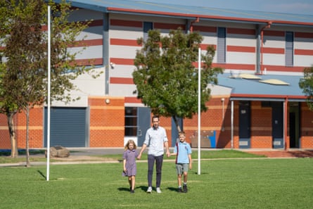 Man and children holding hands and walking in front of goal posts on sports field