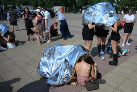 People use emergency blankets to protect them from the heat.