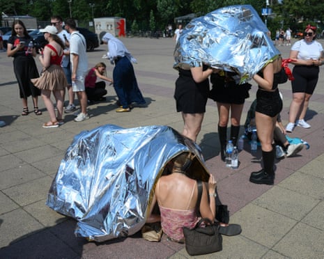 People use emergency blankets to protect them from the heat as the arrive at the Olympic stadium for a concert of US singer Bruno Mars in Berlin, Germany.