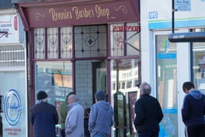 People queue outside to get their hair cut at Ronnie’s Barber Shop in Monkseaton, Whitley Bay, as England takes another step back towards normality with the further easing of lockdown restrictions.