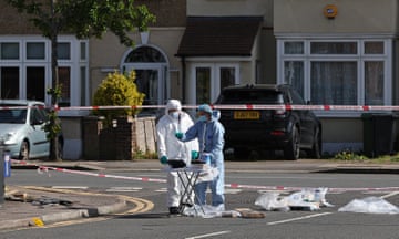 Two forensic scientists collecting bags of evidence on cordoned off street