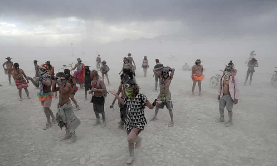 Burning Man participants dance to the music of an art car in a driving desert dust storm in 2017.