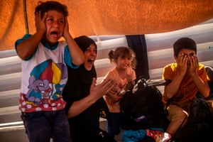 A migrant woman and children react after police fired tear gas during protests near Mytilene.