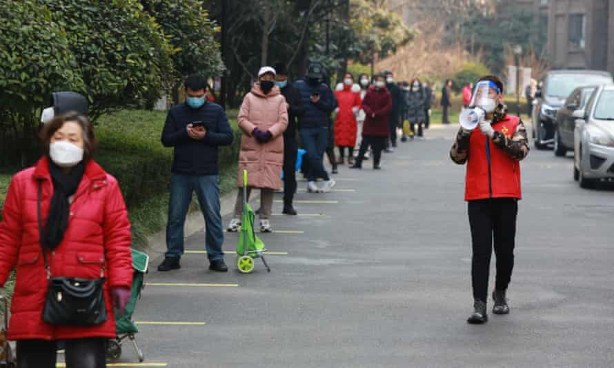 A community volunteer uses a megaphone to remind residents to keep their social distance as they line up to collect their daily necessities outside a residential block in Xi’an.