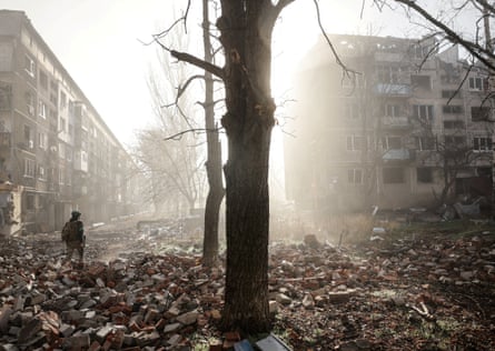 یک سرباز اوکراینی در نزدیکی ساختمانهای آپارتمانی که توسط یک حمله نظامی روسی به شهر لبهجبههٔ کوستینتیوکا آسیب دیدهاند، قدم میزند.