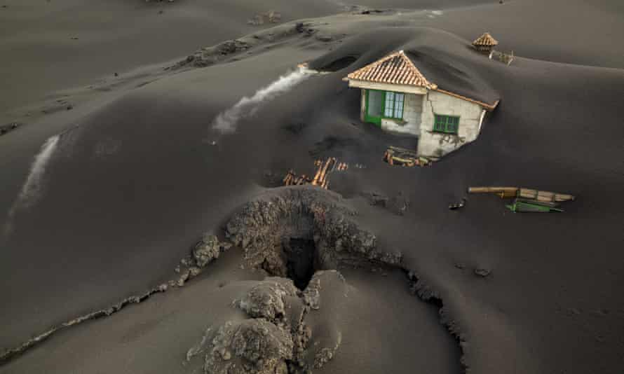 A fissure is seen next to a house covered with ash on La Palma, December 2021.