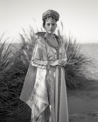 A woman in regal costume on a beach