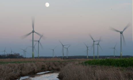 The full moon shines behind a wind park near Norden, Germany.