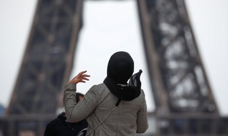 A woman wearing a hijab walks near the Eiffel Tower in Paris, 2 May 2021.